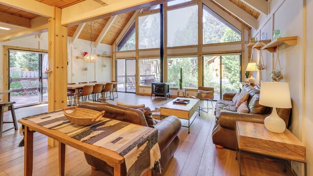 A spacious living area with a high ceiling, large windows, a fireplace, and a cozy seating arrangement.