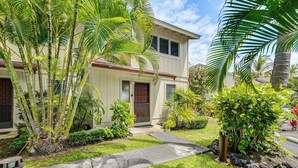A two-story house with a well-maintained lawn, palm trees, and a pathway leading to the front door. - Ultimate Oceanfront Townhome w/ A/C On Kona Coast (Kailua-Kona)