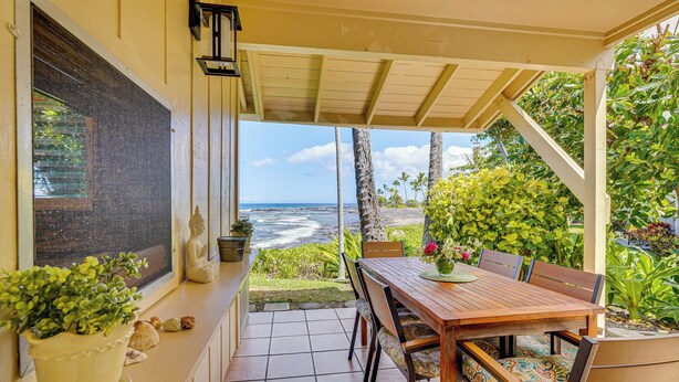 A covered patio with a wooden table and chairs, a potted plant, and a view of the ocean. - Ultimate Oceanfront Townhome w/ A/C On Kona Coast (Kailua-Kona)