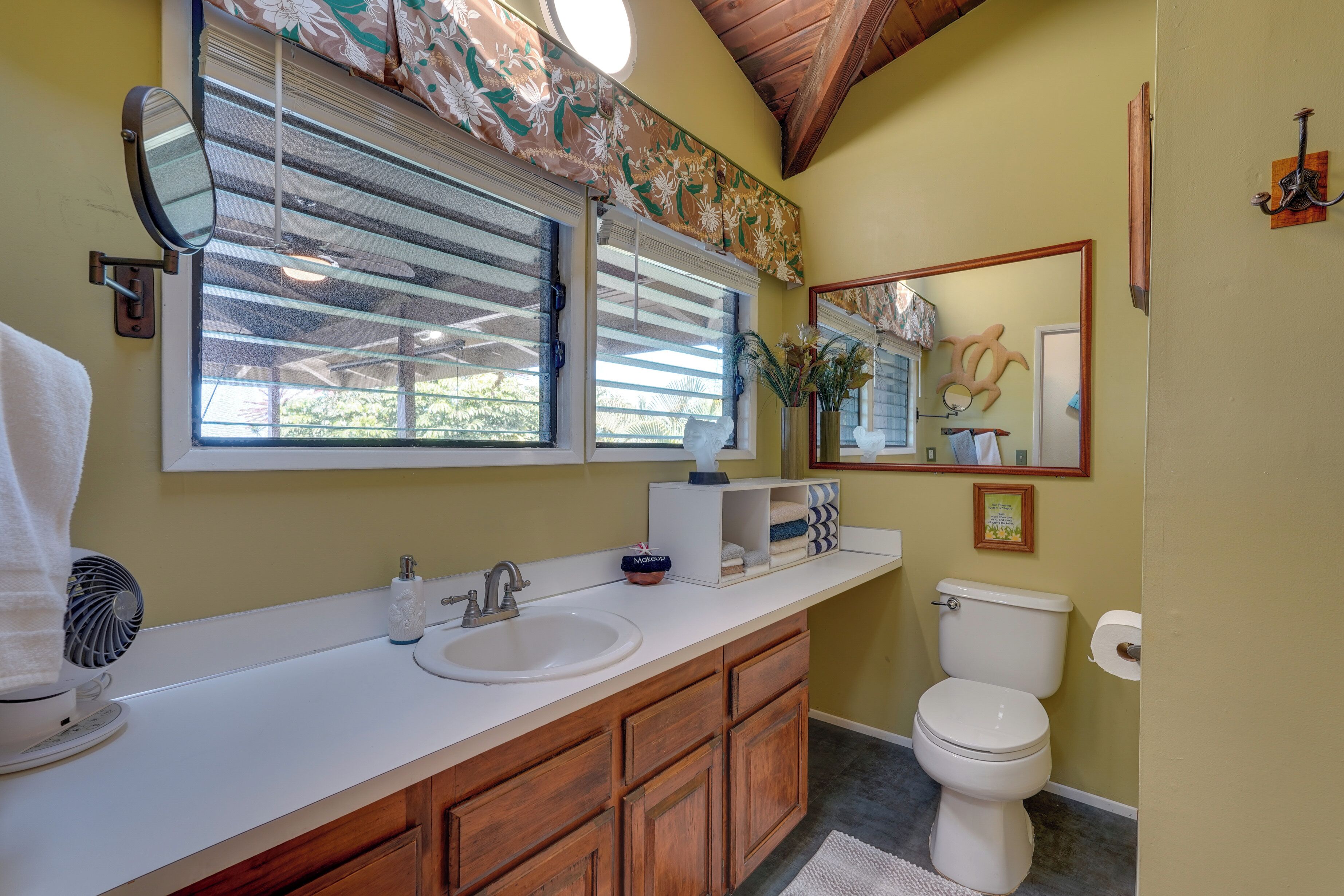 A bathroom with a white sink, wooden cabinets, a toilet, and a large mirror.