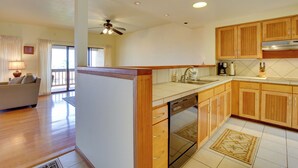 A kitchen with wooden cabinets, a dishwasher, and a ceiling fan. - Kailua-kona Condo w/ Resort Access & Ocean View! (Kailua-Kona)