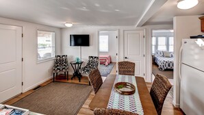 A dining area with a wooden table, woven chairs, and a television on the wall.