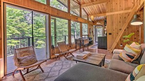 A spacious wooden interior with large windows, a cozy seating area, and a staircase. - High Falls Restorative Cabin in the Woods! (High Falls)