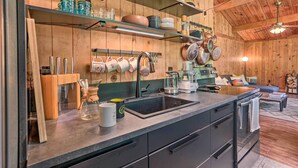 A kitchen with wooden walls, a sink, and various kitchen utensils. - High Falls Restorative Cabin in the Woods! (High Falls)