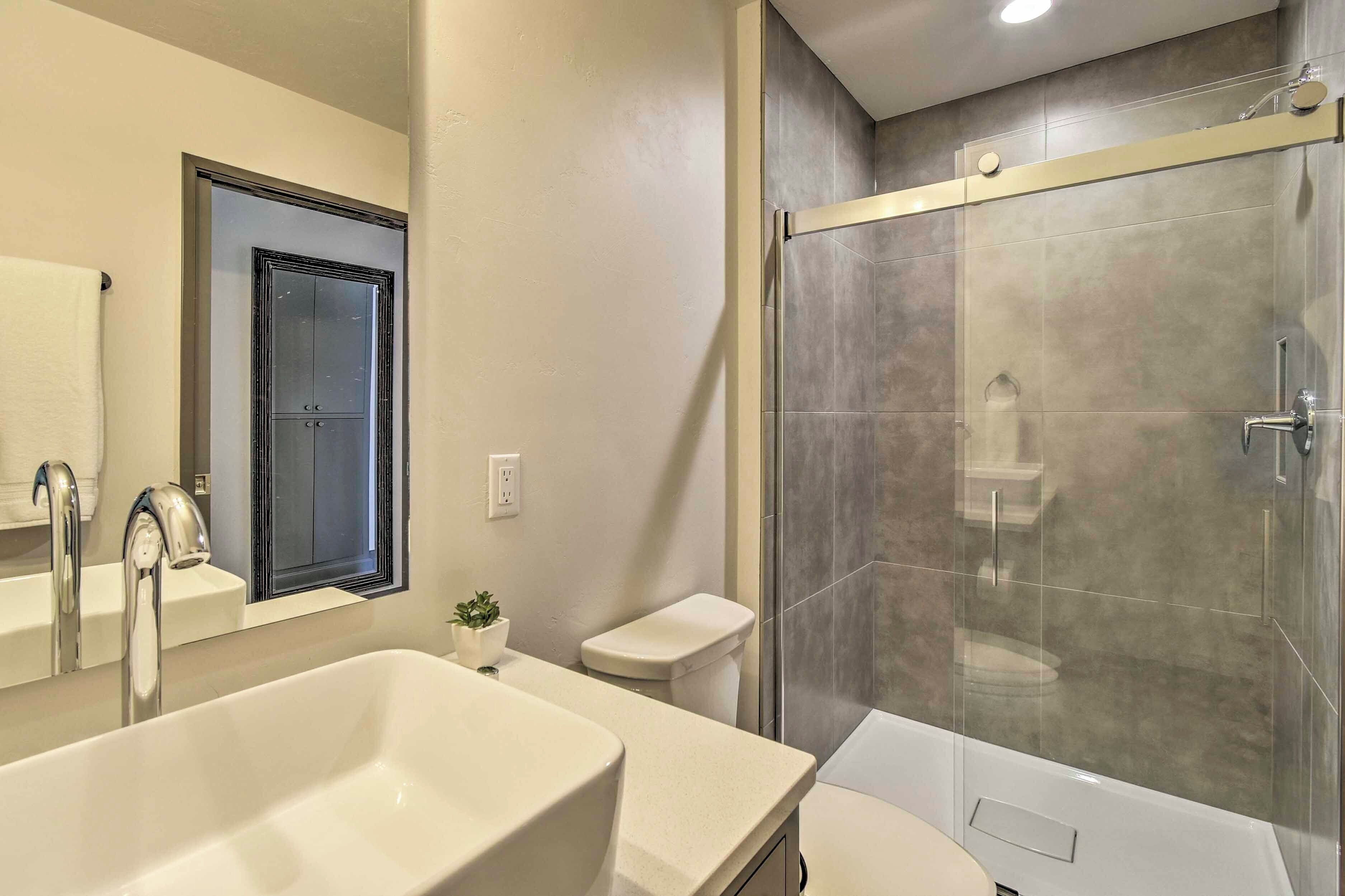 A modern bathroom with a large sink, a toilet, and a glass-enclosed shower.