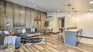 Un salon moderne avec un canapé, une table basse et un coin repas avec des chaises. Il y a également une cuisine équipée d’un évier et d’un plan de travail.