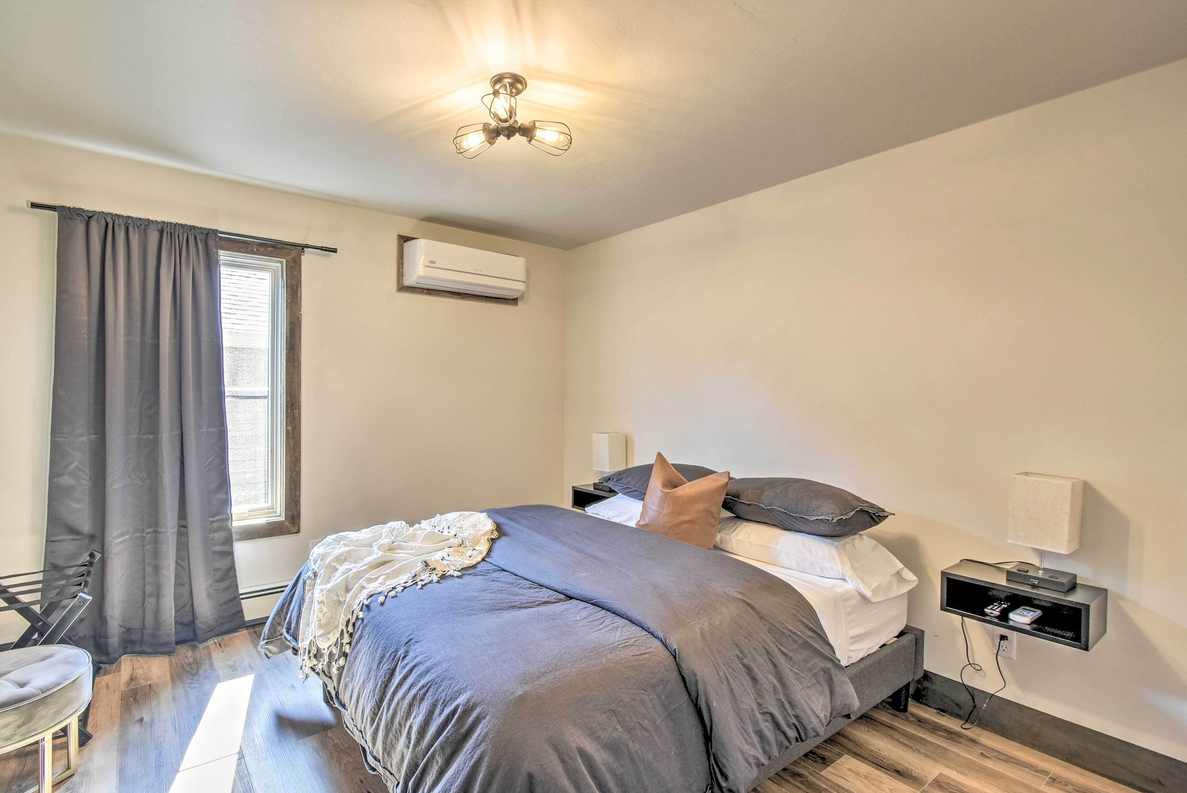 A bedroom with a bed, bedside tables, a nightstand, a lamp, and a window with curtains.