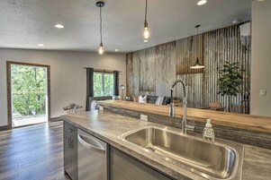 Una cocina moderna con una isla grande, un lavamanos de acero inoxidable e iluminación colgante.