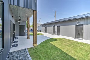 A modern building with a covered walkway, multiple doors, and a well-maintained lawn.