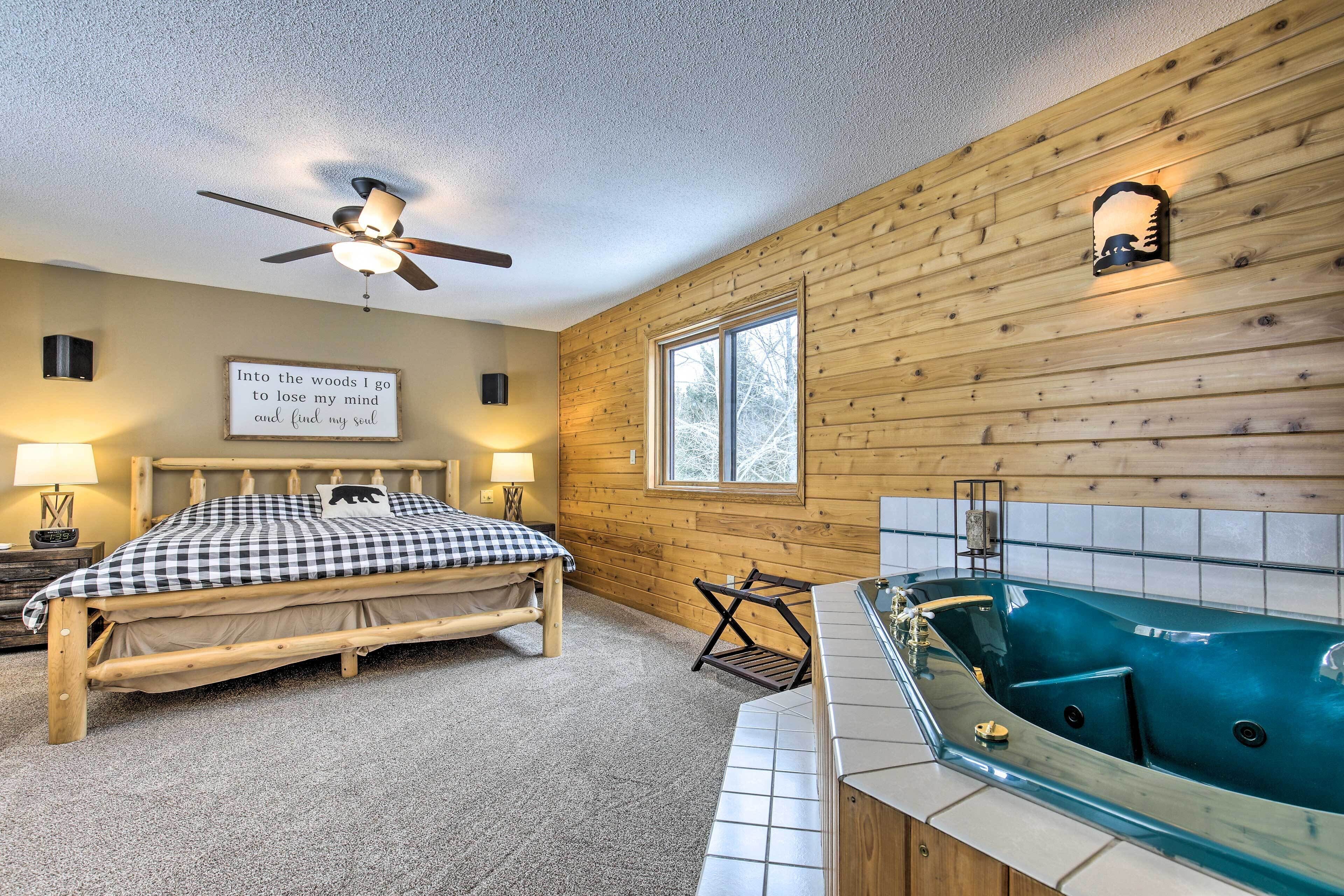 A bedroom with a bed, a ceiling fan, a window, a sign, and a bathtub.