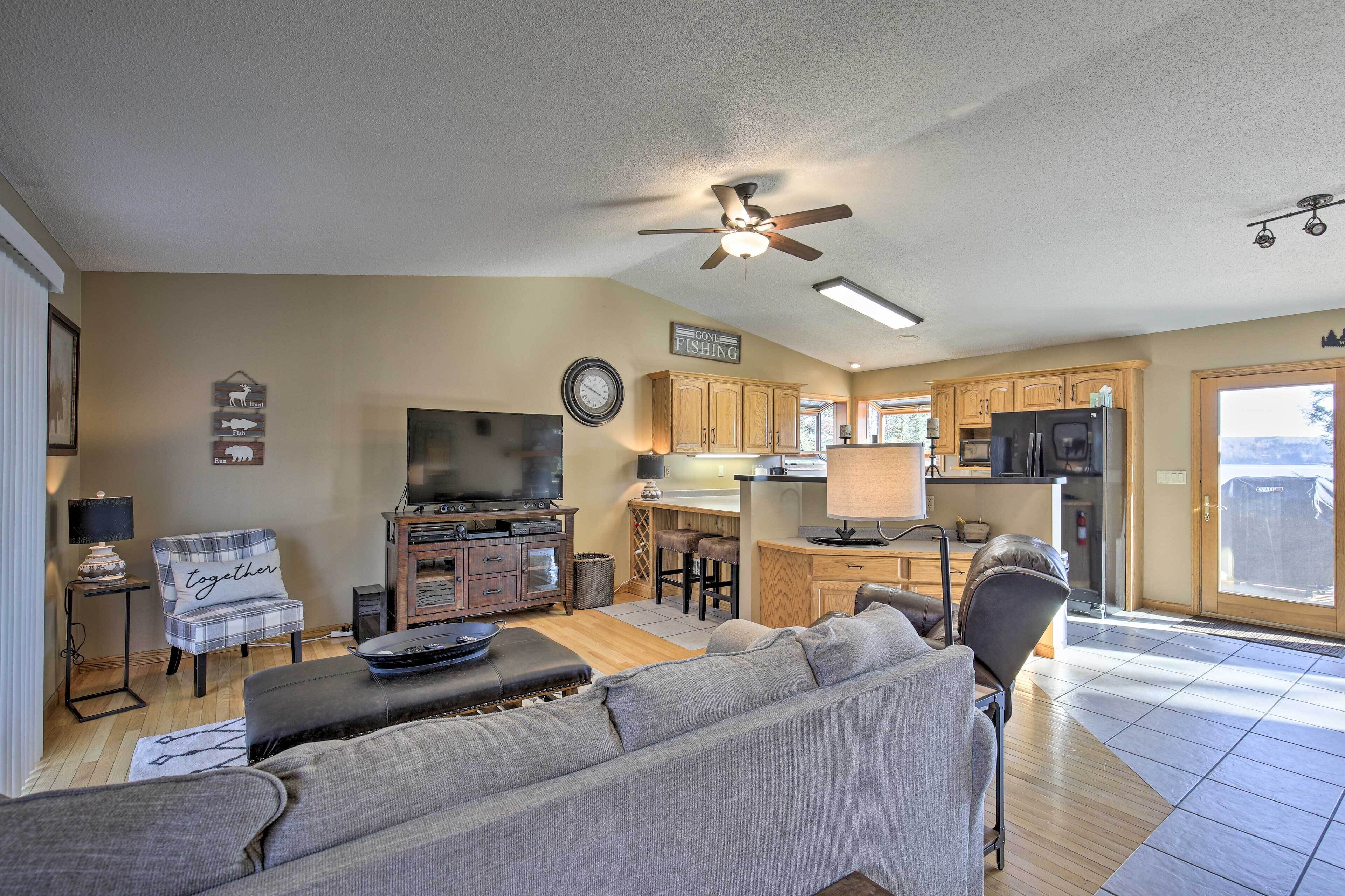 A spacious living room with a gray sofa, a television, and a ceiling fan.