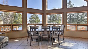 A dining area with a table and chairs, large windows, and a view of trees and a body of water. - Secluded Lakehouse w/ Private Dock + Serene Views! (Iron River)