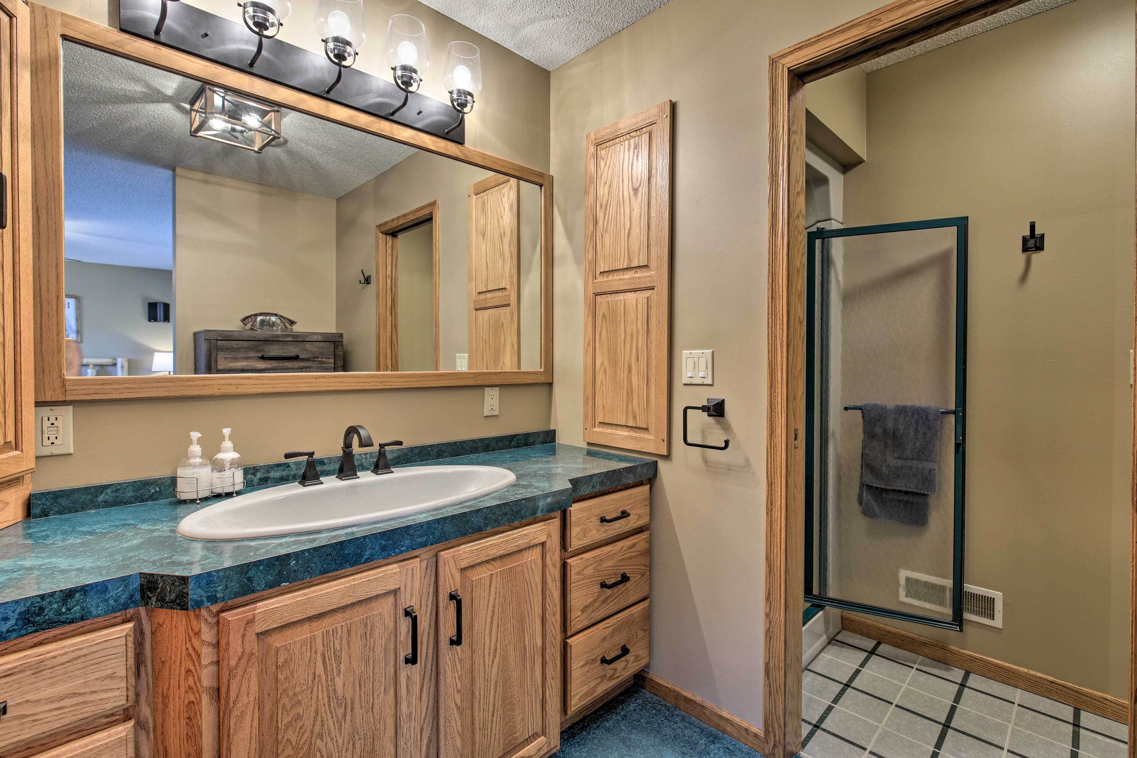 Un baño con tocador de madera, un espejo grande, un lavabo y cabina de ducha de vidrio.