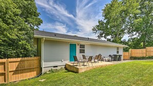 Une maison de plain-pied avec un porche à l’avant, une porte bleue et un petit patio avec quatre chaises.