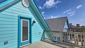 Un bâtiment turquoise doté d’une terrasse en bois et d’un balcon.