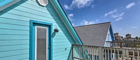 Een turquoise gebouw met een houten terras en een balkon.
