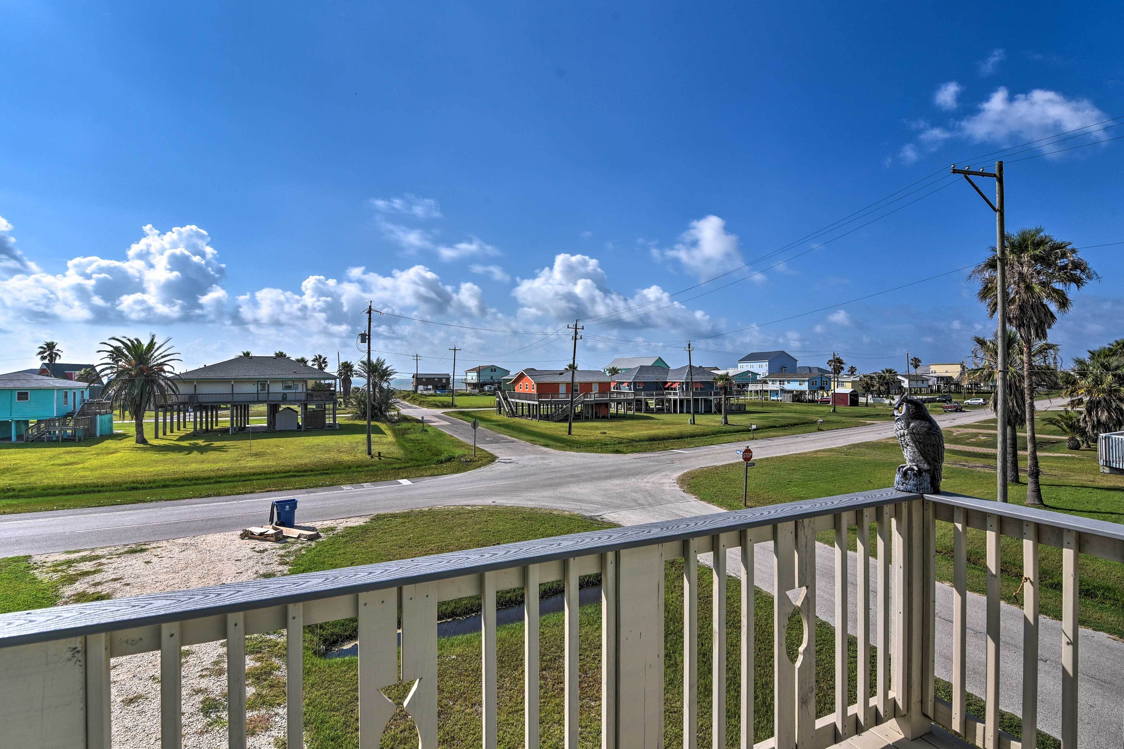 A residential area with houses, a road, and a statue on a balcony.