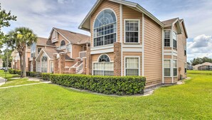 A two-story house with a large arched window, brick exterior, and a well-maintained lawn.