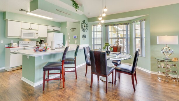 A kitchen with a central island, wooden chairs, and a dining table with chairs.