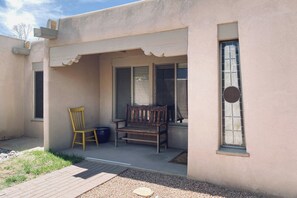 A building with a porch, a wooden bench, a chair, and a window.