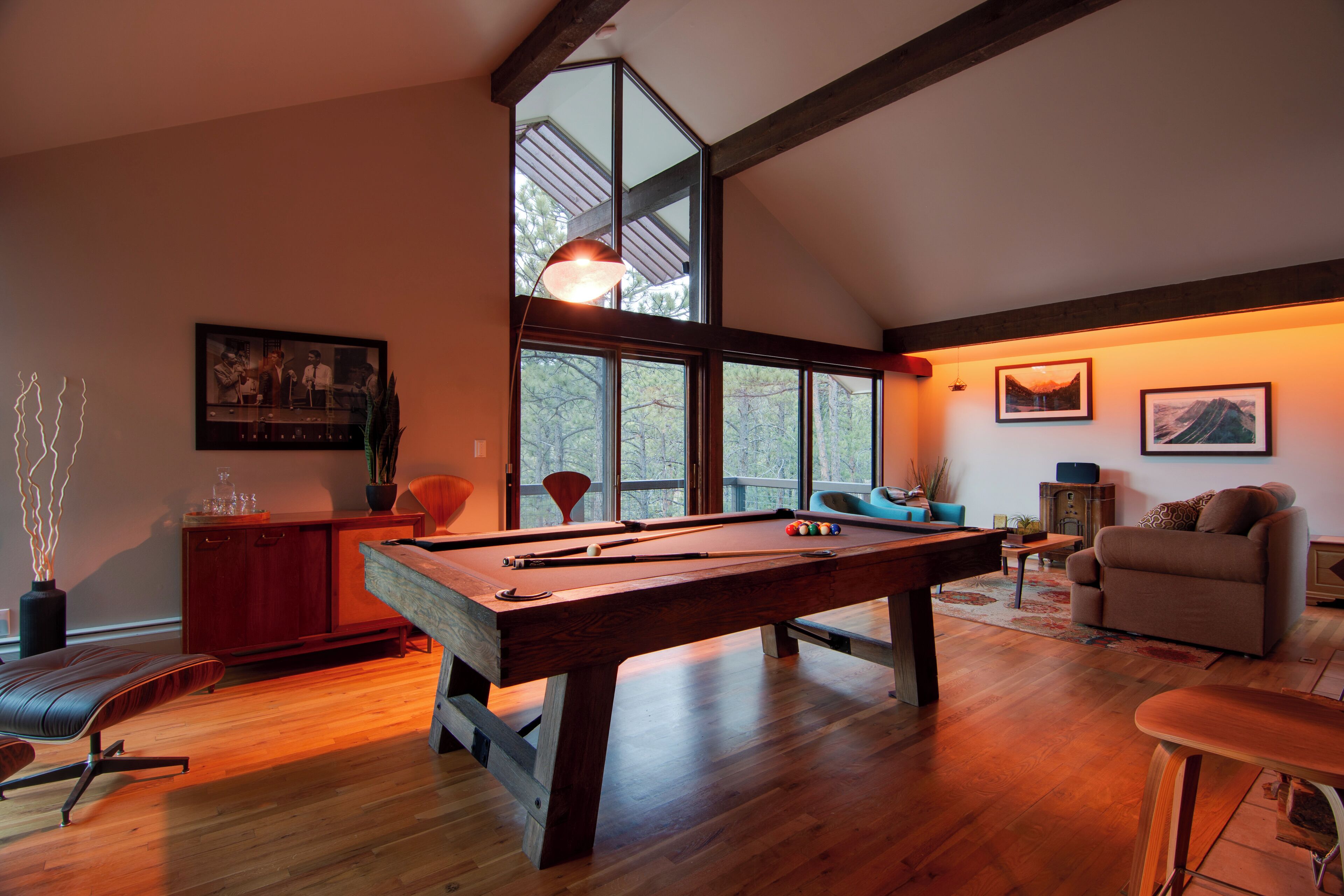 Una habitación amplia con mesa de billar, un sofá cómodo y un ventanal que ofrece vistas al exterior.