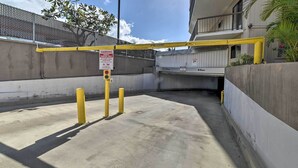 Een omheind parkeergebied met een gele barrière en een waarschuwingsbord met parkeerbeperkingen.