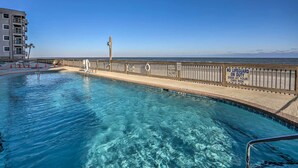 A swimming pool with a wooden deck and a lifeguard stand, surrounded by a high fence with warning signs. - Oceanfront Oasis w/ Deck and Resort Beach Access! (Murrells Inlet)