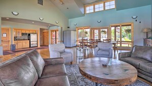 A spacious living area with leather sofas, a round coffee table, and a dining area with wooden furniture.
