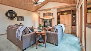 A cozy living room with a fireplace, wooden ceiling, and built-in wooden cabinets.