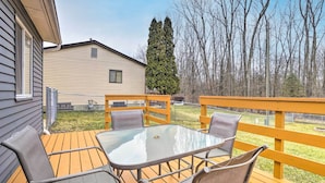 A wooden deck with a glass table and four chairs, a yellow railing, and a house in the background. - Charming Columbus Home ~ 7 Mi to Ohio State! (Columbus)