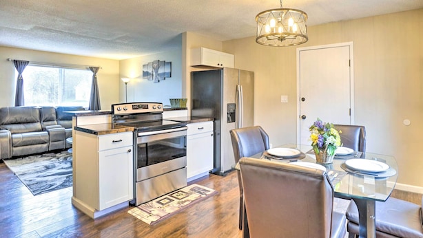 A modern kitchen with stainless steel appliances, a dining area with a glass table, and a living room with a gray sofa. - Charming Columbus Home ~ 7 Mi to Ohio State! (Columbus)