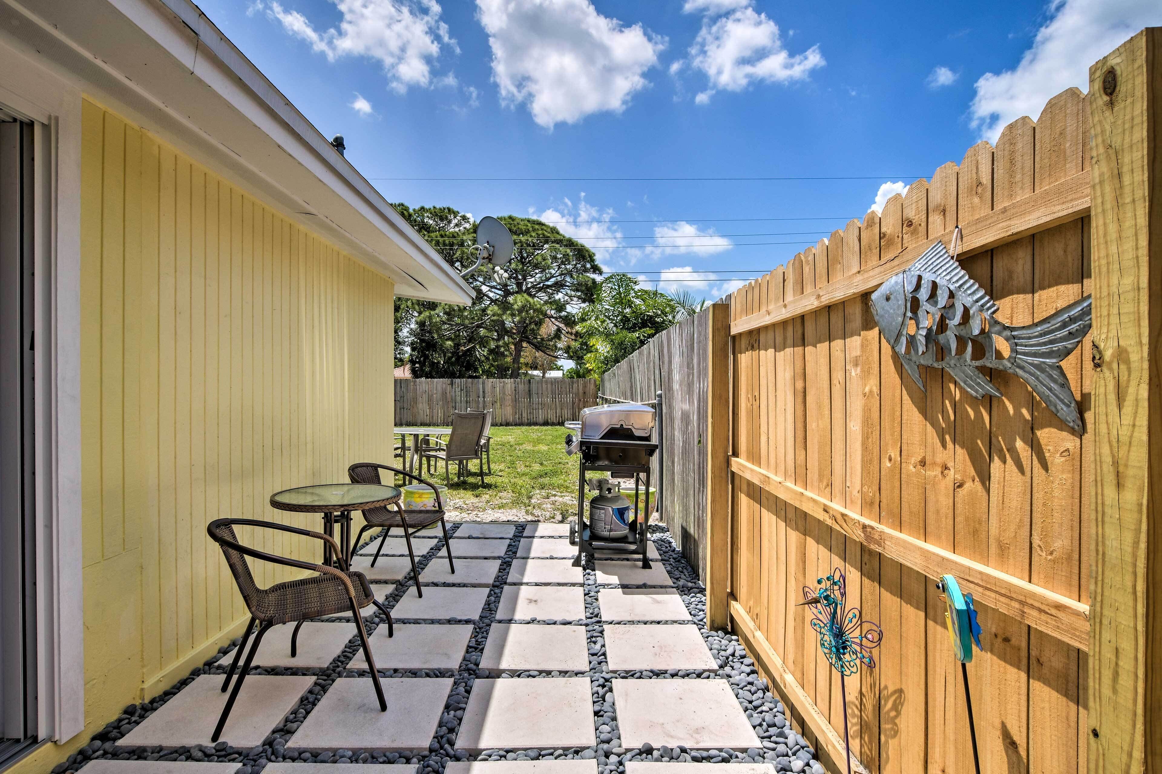 A patio with outdoor furniture, a grill, and decorative fish on a wooden fence.