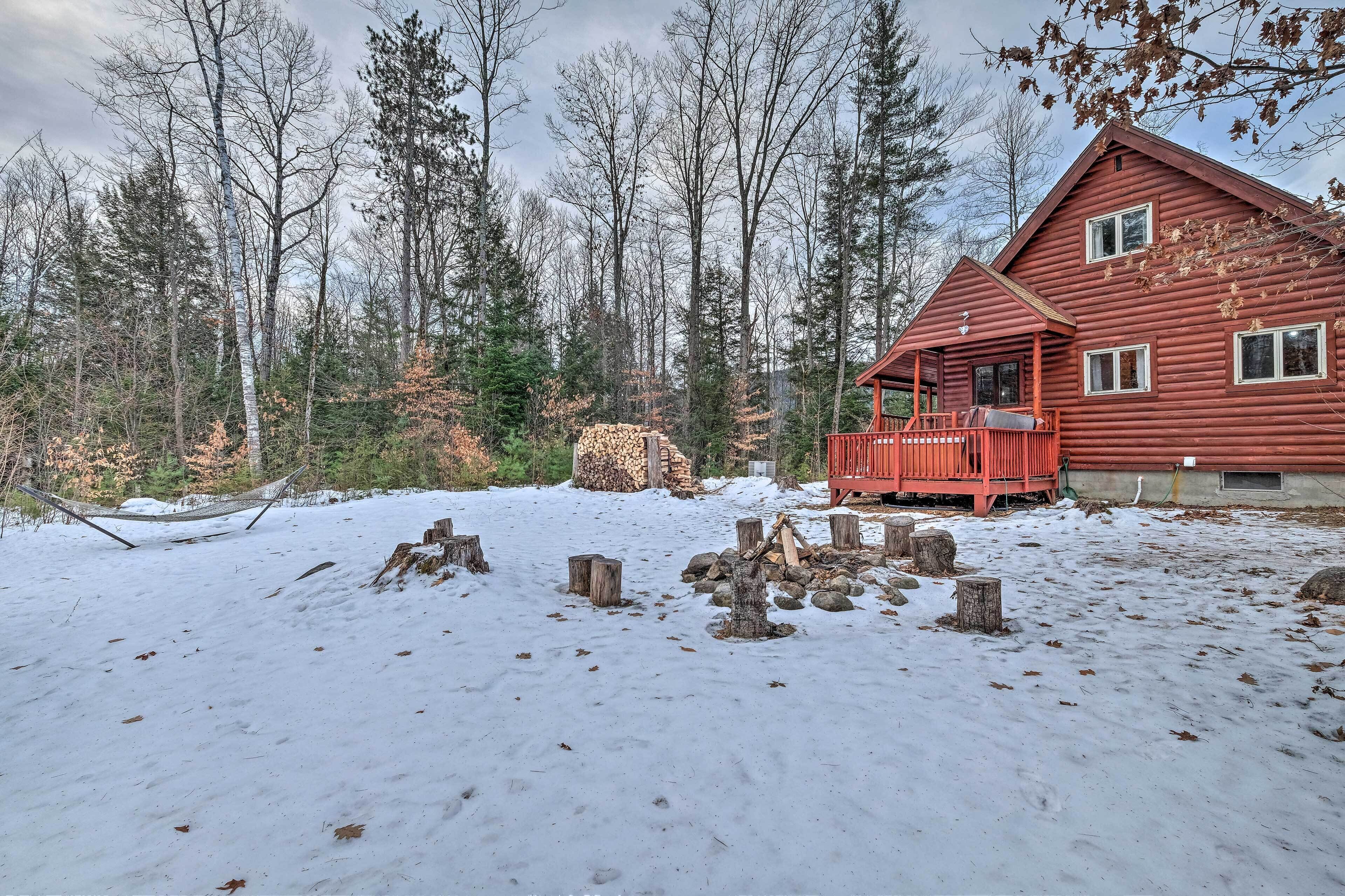 Une cabane dotée d’une terrasse en bois, entourée d’une forêt enneigée.