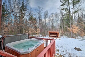 Ein Whirlpool auf einer Holzterrasse mit Blick auf einen verschneiten Wald.