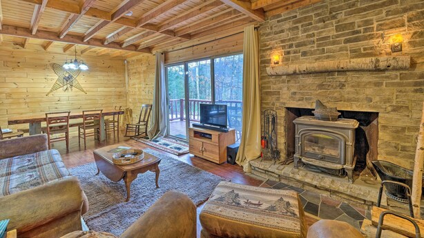 A cozy cabin interior with a fireplace, wooden furniture, and a television. - Secluded Johnsburg Retreat w/ Hot Tub & Fire Pit (Johnsburg)