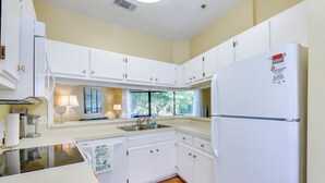 A compact kitchen with white cabinets, a built-in sink, and a refrigerator.