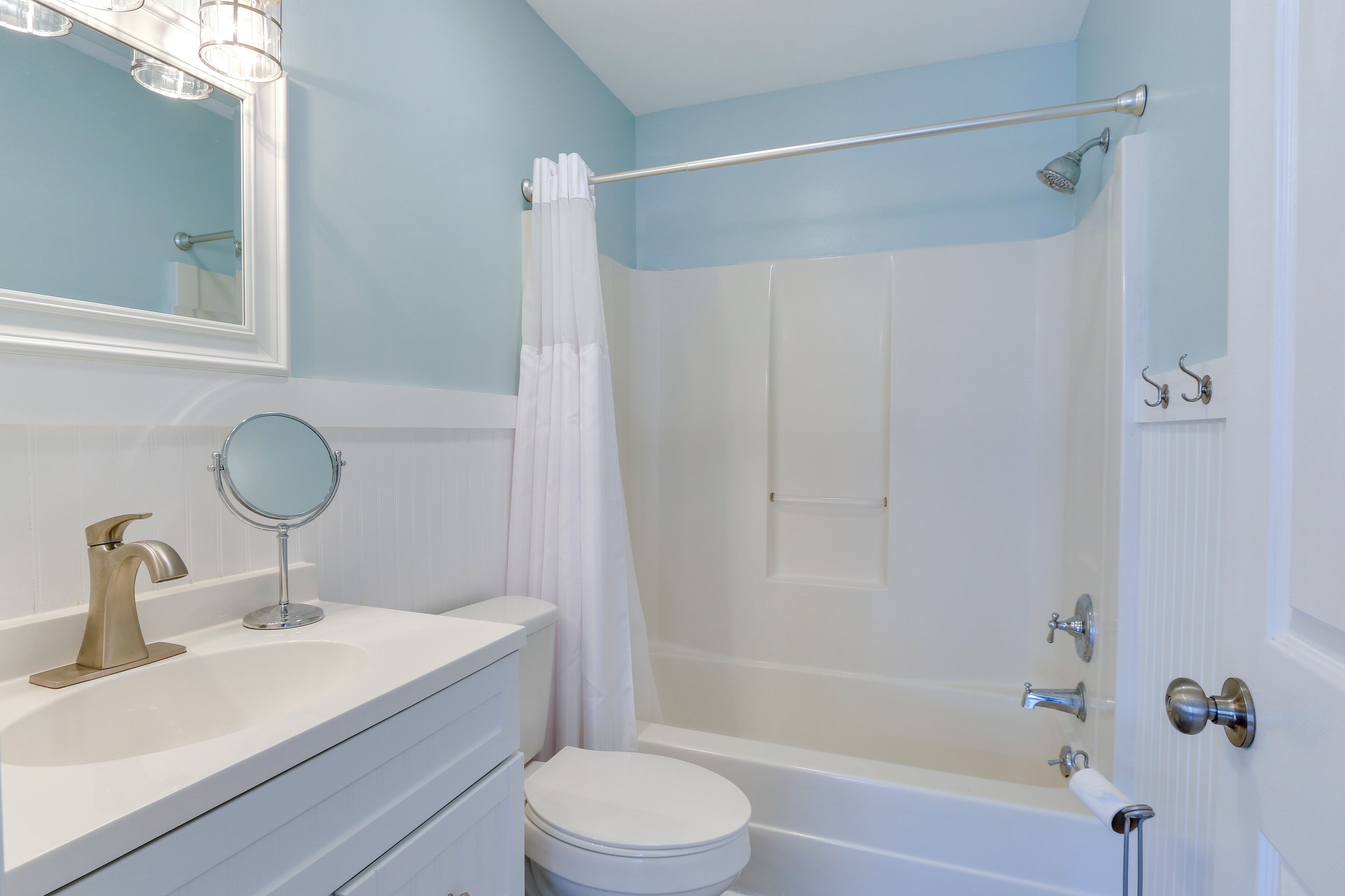 A bathroom with a white sink, a round mirror, a toilet, and a bathtub.