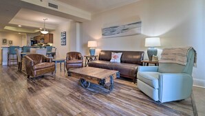 A spacious living room with a wooden coffee table, leather sofas, and a ceiling fan. - Dauphin Island Condo w/ Pool, Balcony & Ocean View (Dauphin Island)