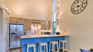 A modern kitchen with a blue island, stainless steel appliances, and a decorative clock.
