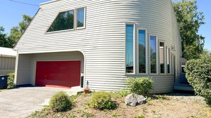 A modern, single-story house with a red garage door, large windows, and a curved roofline.