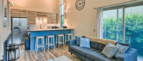 A modern kitchen with a central island, bar stools, and a large window.