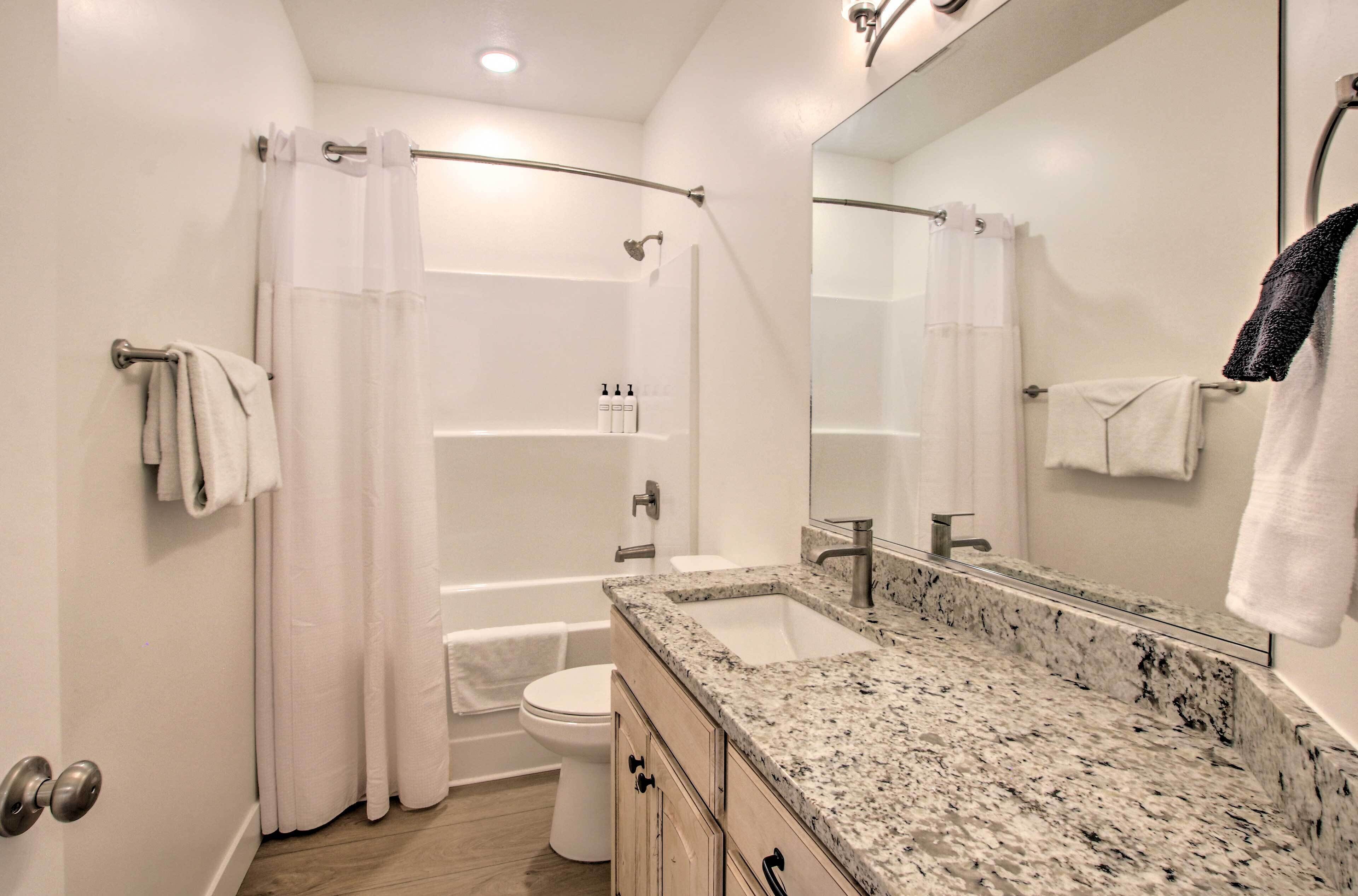 A modern bathroom with a shower, toilet, and sink.