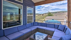 A covered outdoor seating area with a large sectional sofa and a glass table, overlooking a residential neighborhood. - Garden City Retreat w/ Access to Bear Lake! (Garden City)