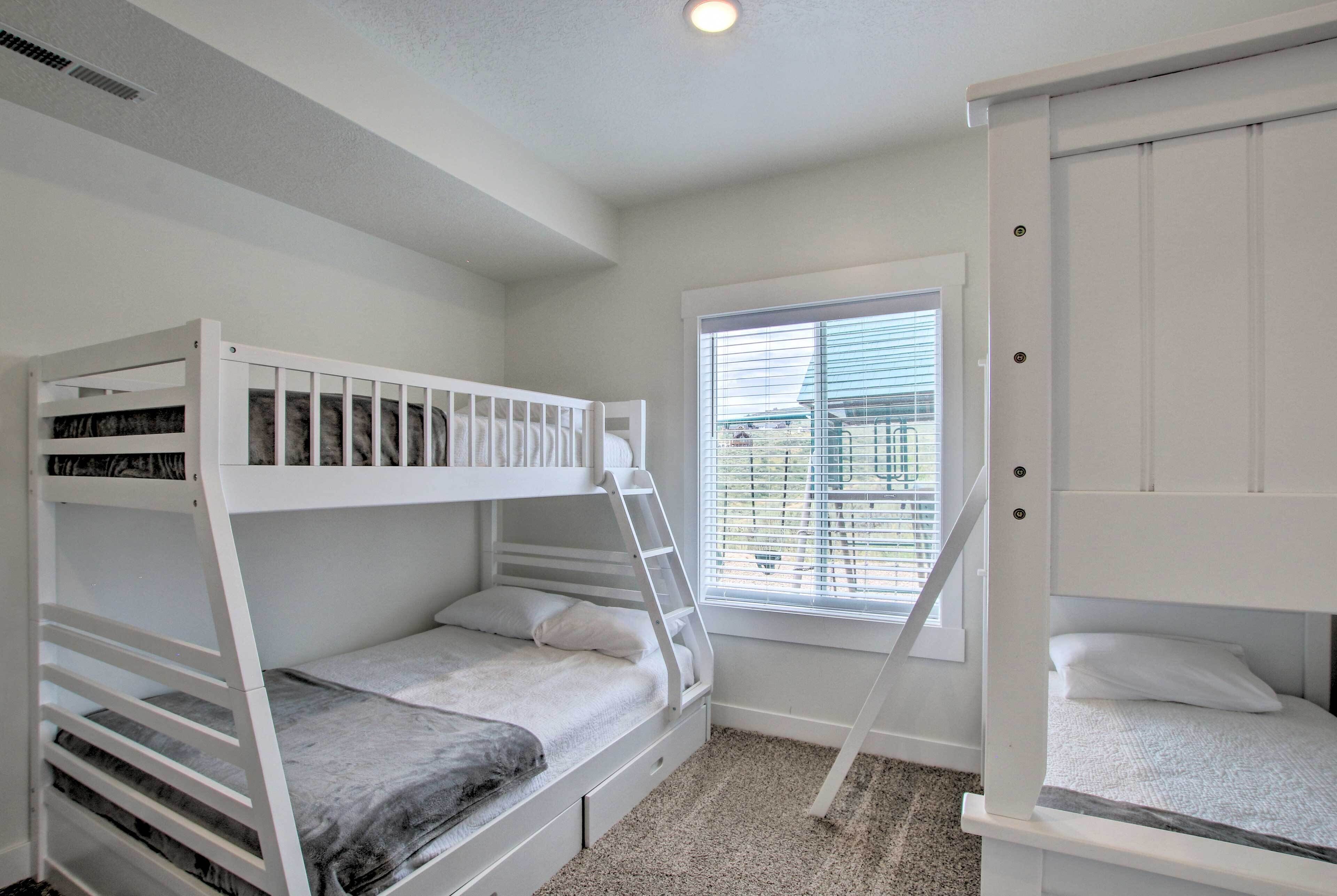 A room with two bunk beds, a window with blinds, and a ladder.