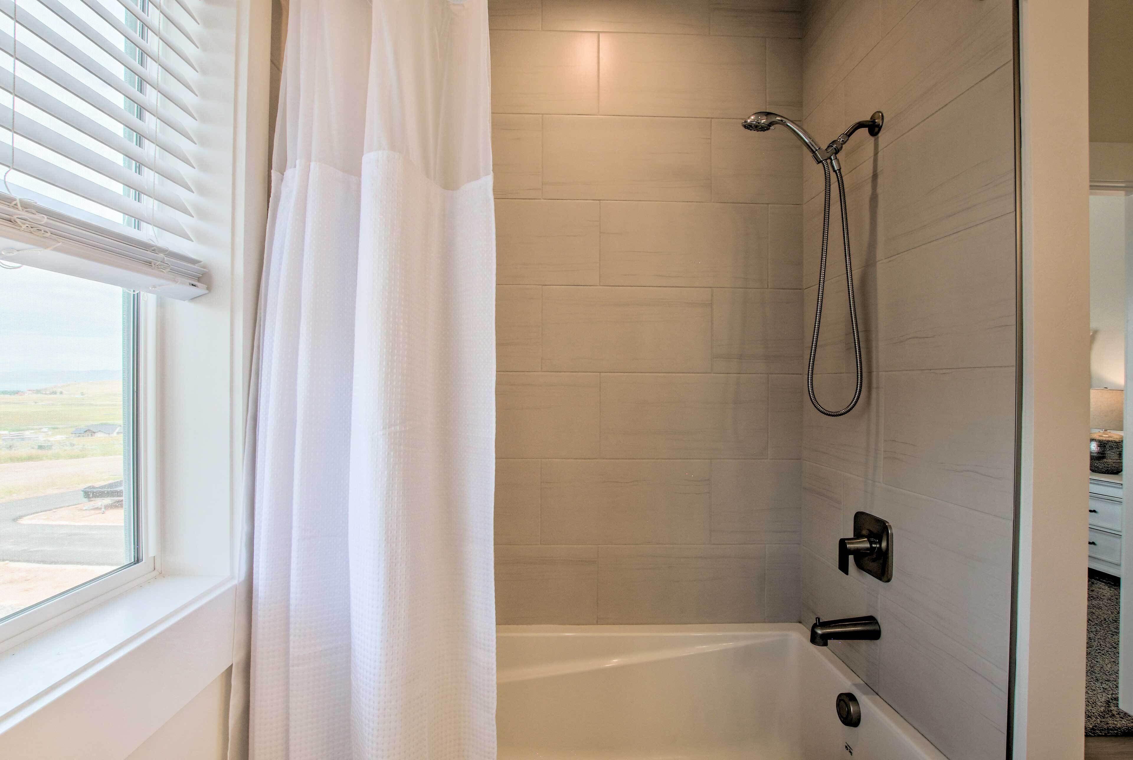 Un baño moderno con ducha, bañera y ventana con persianas.