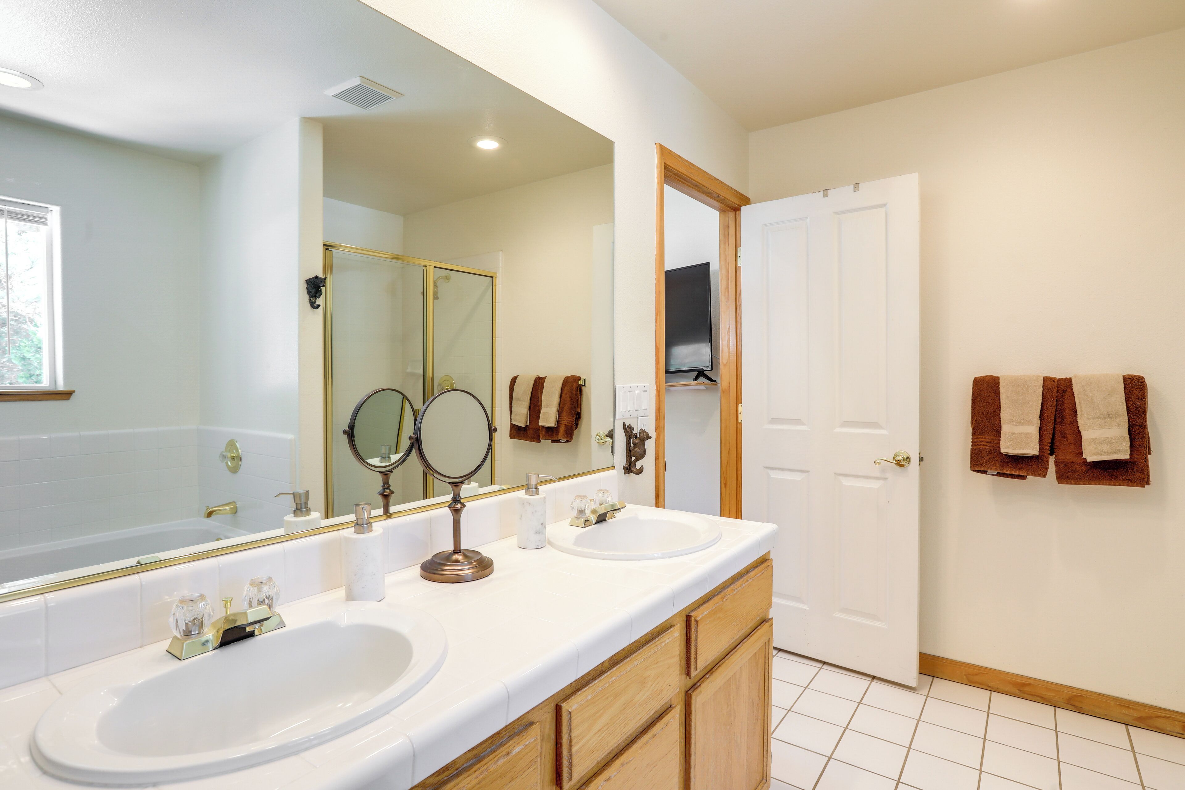 Une salle de bain avec deux lavabos, un grand miroir et des meubles en bois.