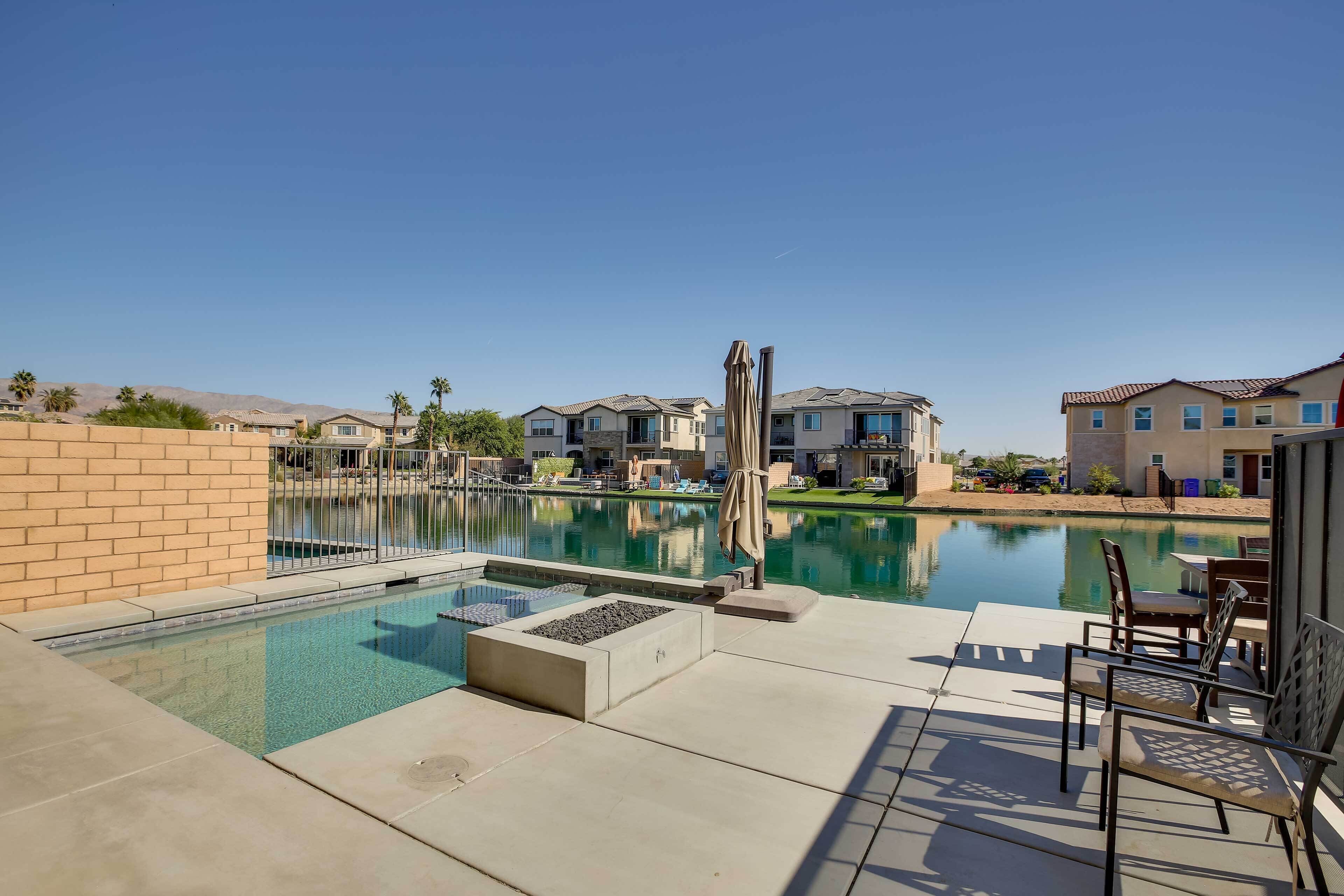 Una piscina amb zona de terrassa, seients de relax i vista a edificis residencials.