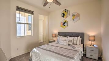 A bedroom with a bed, two bedside tables, a ceiling fan, and artwork on the wall.