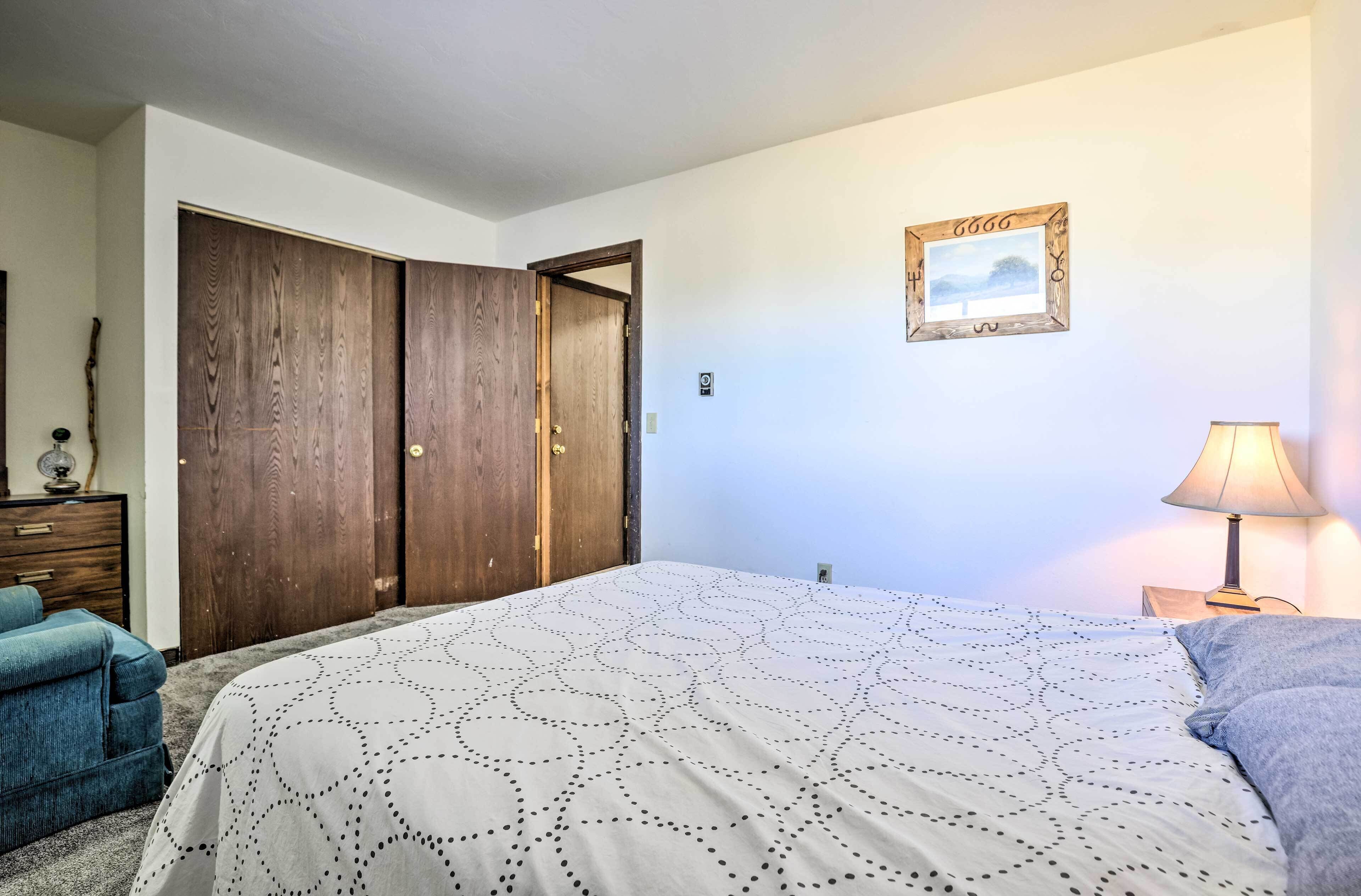 Une chambre à coucher comprenant un lit, une commode, une armoire, une lampe et un tableau encadré accroché au mur.