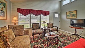 A living room with patterned furniture, a television, and a large window with blinds.